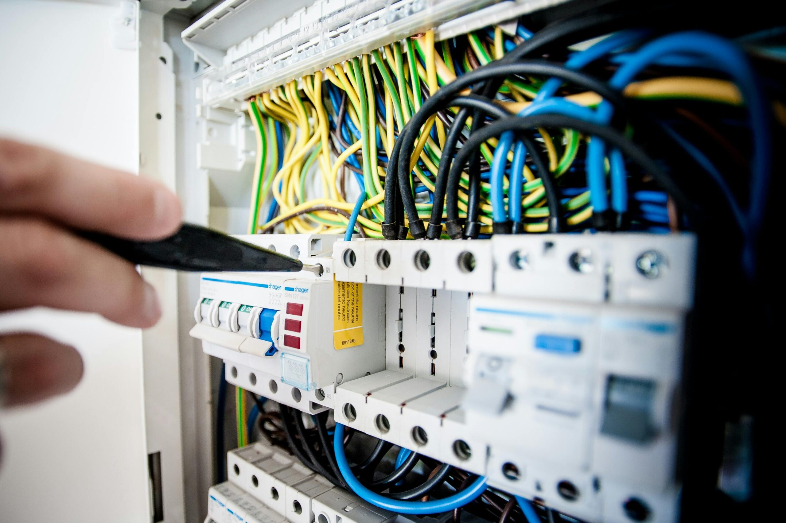 pexels-photo-257736-257736 Hand of electrician working on a circuit breaker panel with colorful wires, ensuring safe electrical connections.